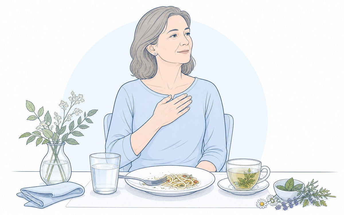 Was hilft gegen Sodbrennen? Frau nach dem Essen mit der Hand auf der Brust, daneben Wasser und Kräutertee